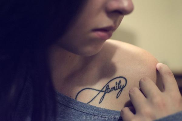 collarbone tattoo with infinity symbol and family lettering