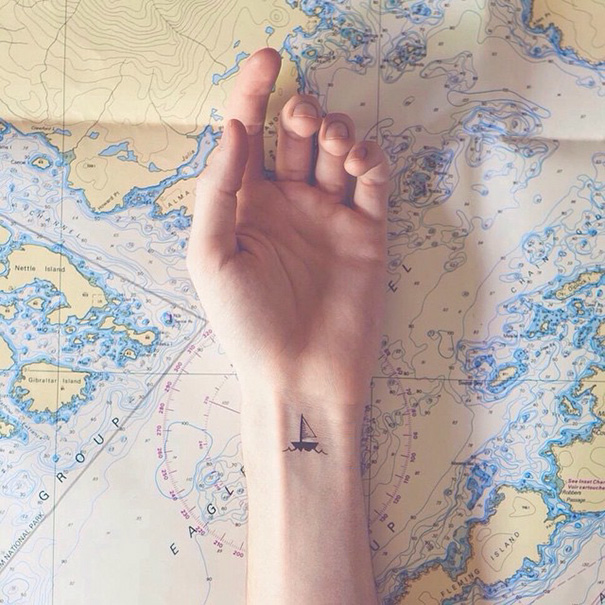 Tiny black boat wrist tattoo