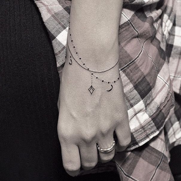 Wrist with black, minimal bracelet tattoo