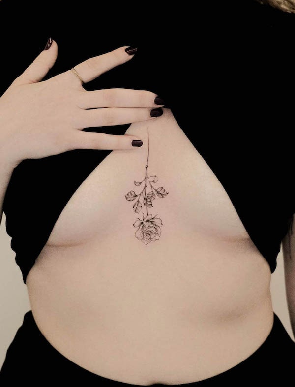 Reversed rose tattoo between boobs by @jk.tattoo