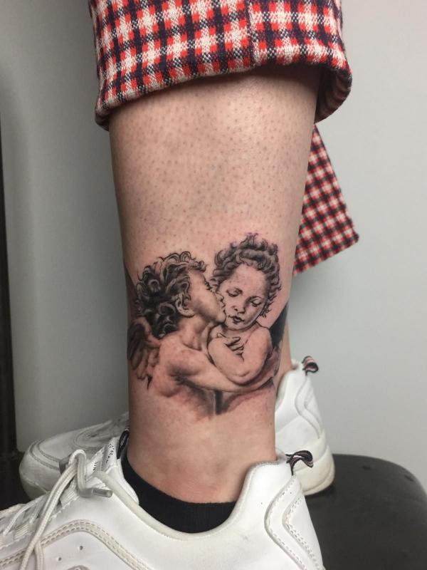 Small kissing cupid tattoo above ankle