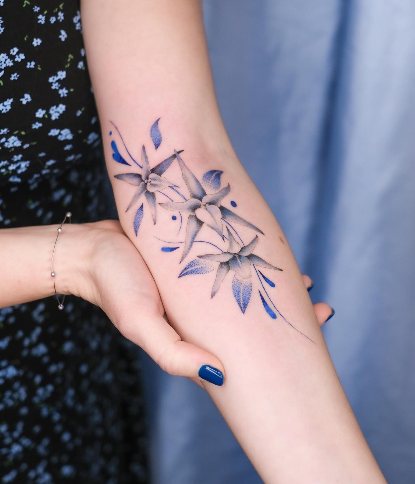 Blue orchids tattooed on  the inner forearm, illustrative style