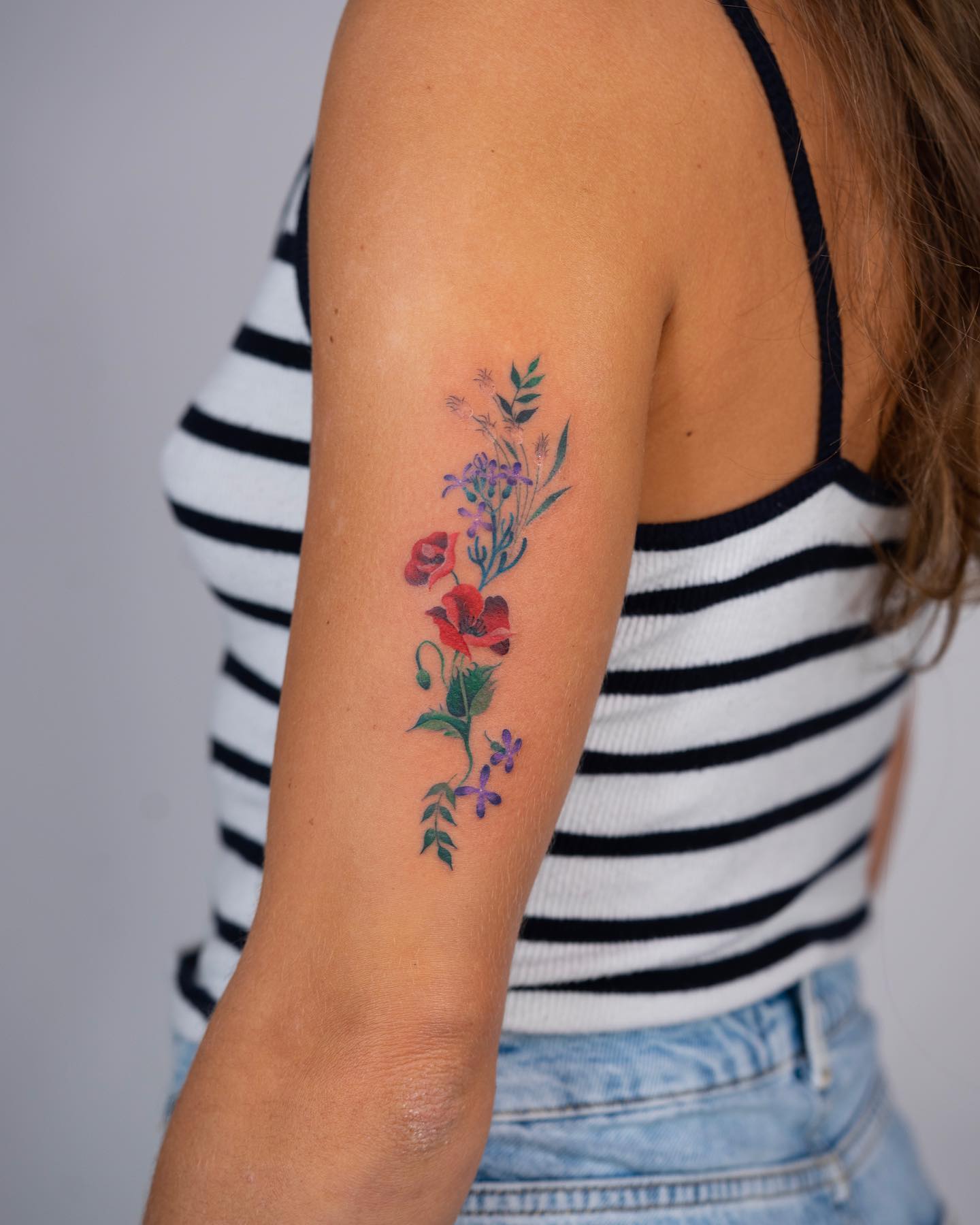 Colorful floral tattoo located on the outer arm