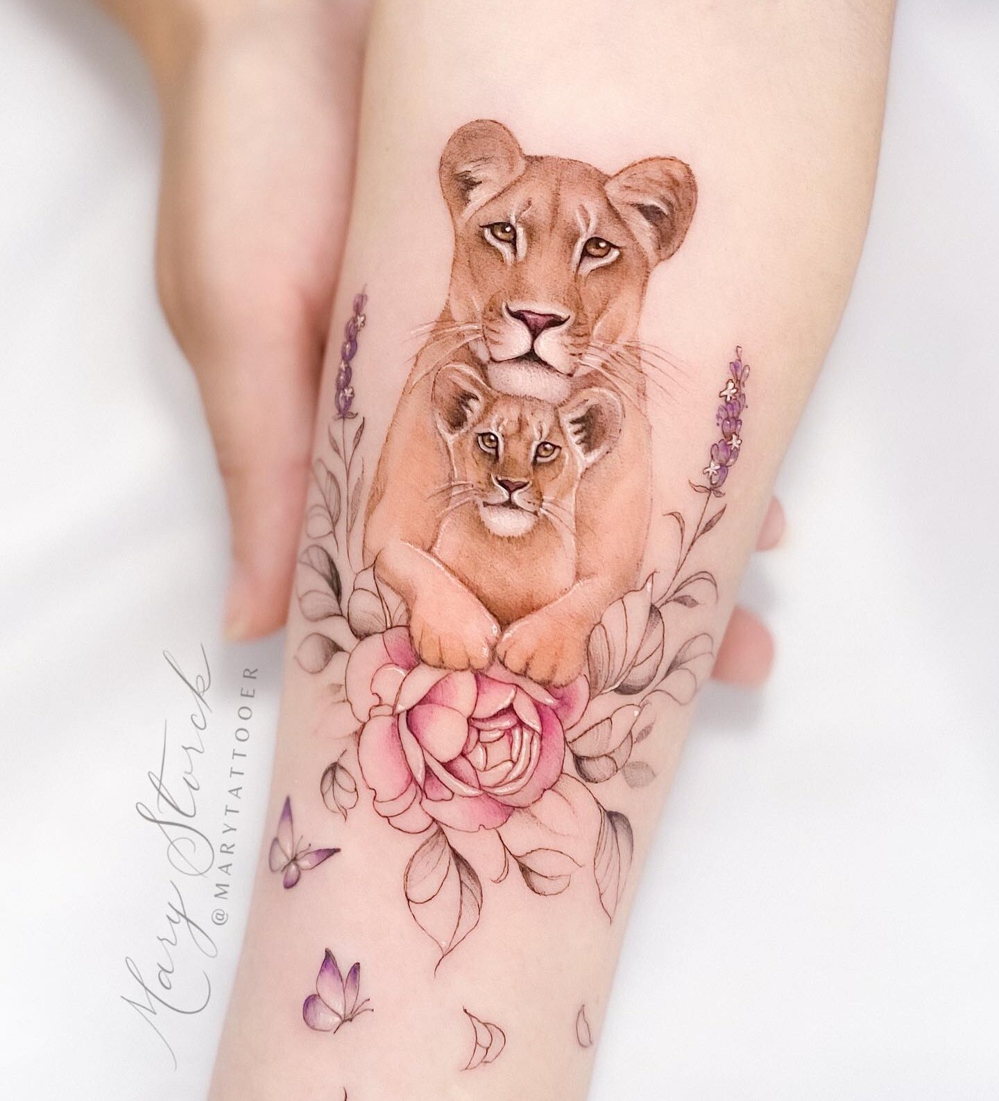 Lioness and lion cub tattoo on the forearm