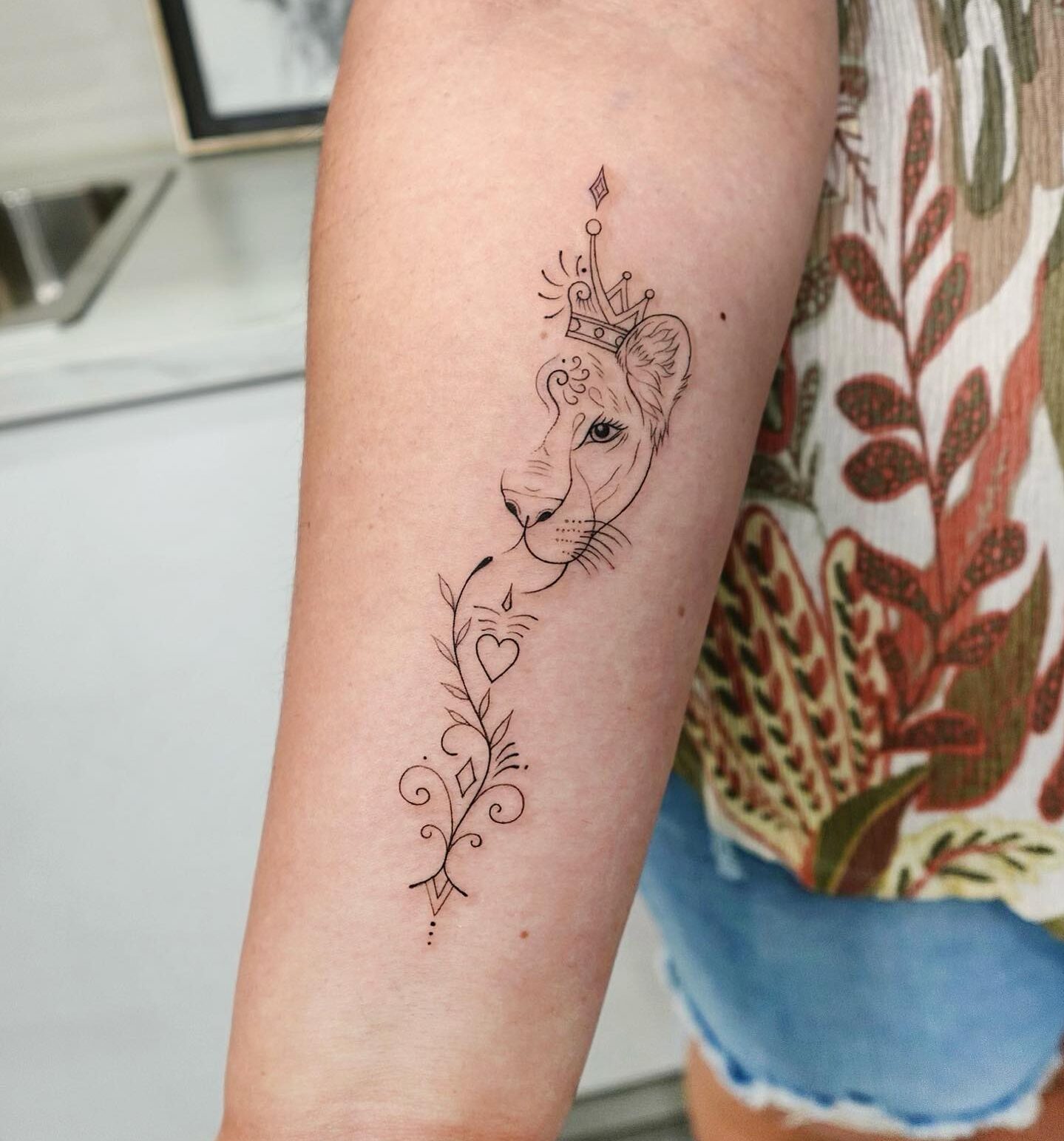 Line work style lioness tattoo on the forearm