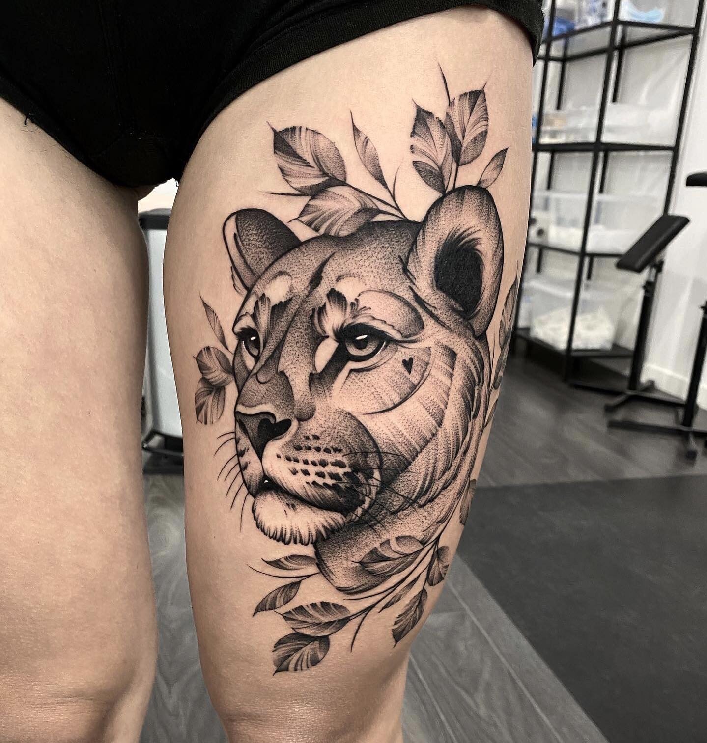 Huge lioness with leaves tattooed on the thigh