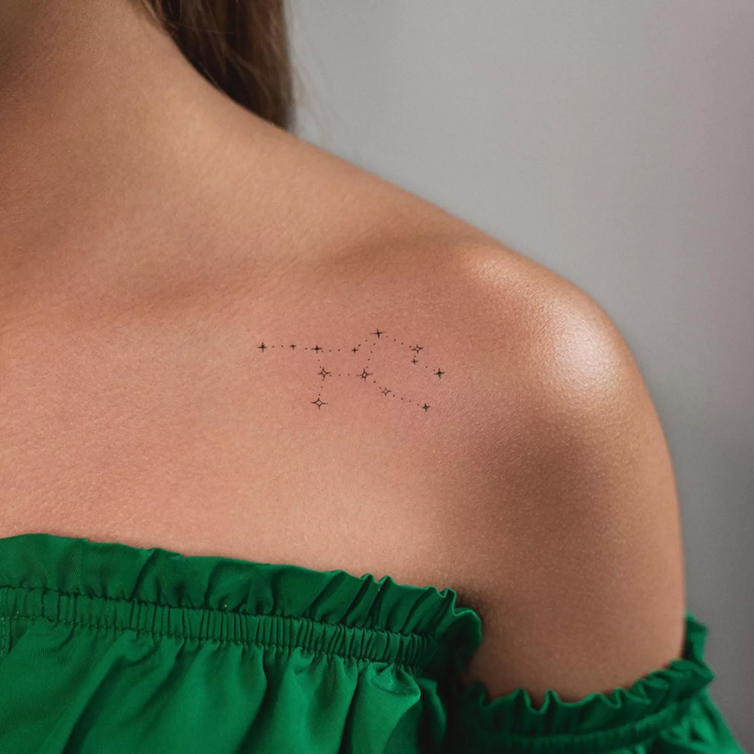 zoomed-in image of model with dainty constellation tattoo on collarbone