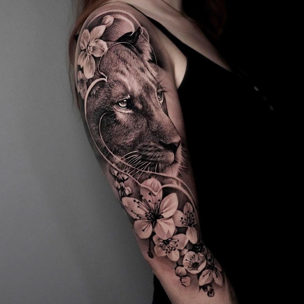 Huge lioness with flowers tattoo on the arm