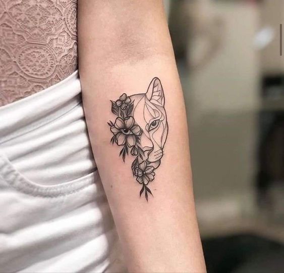 Half lioness and half flowers tattoo on the inner forearm