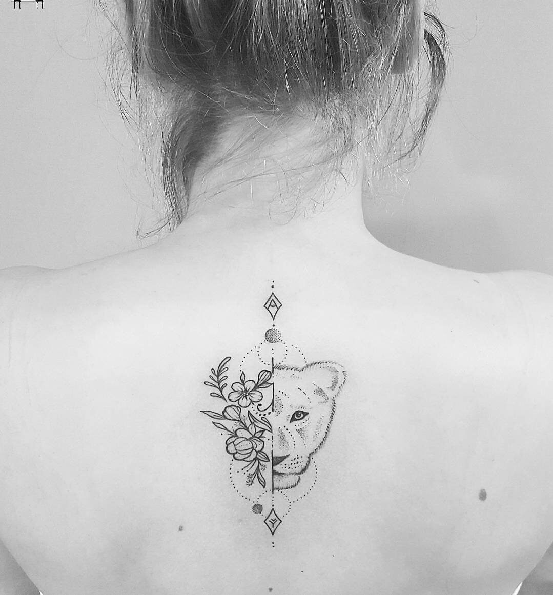 Half lioness and half flowers tattoo on the upper back