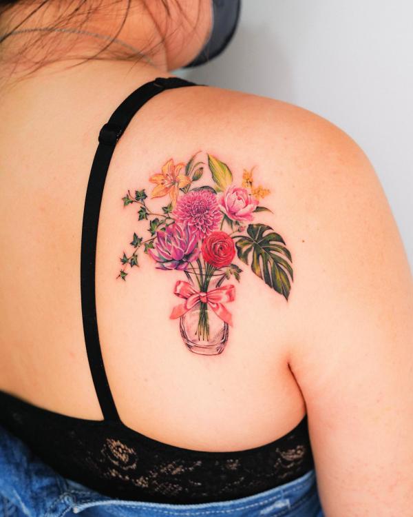 A bouquet of flowers in bottle with dahlia rose daffodil tattoo