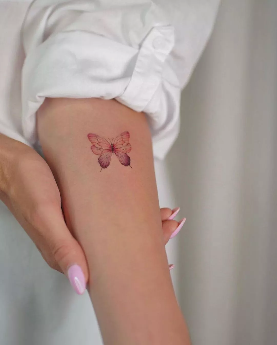 Close up of a red and purple butterfly tattoo on the arm