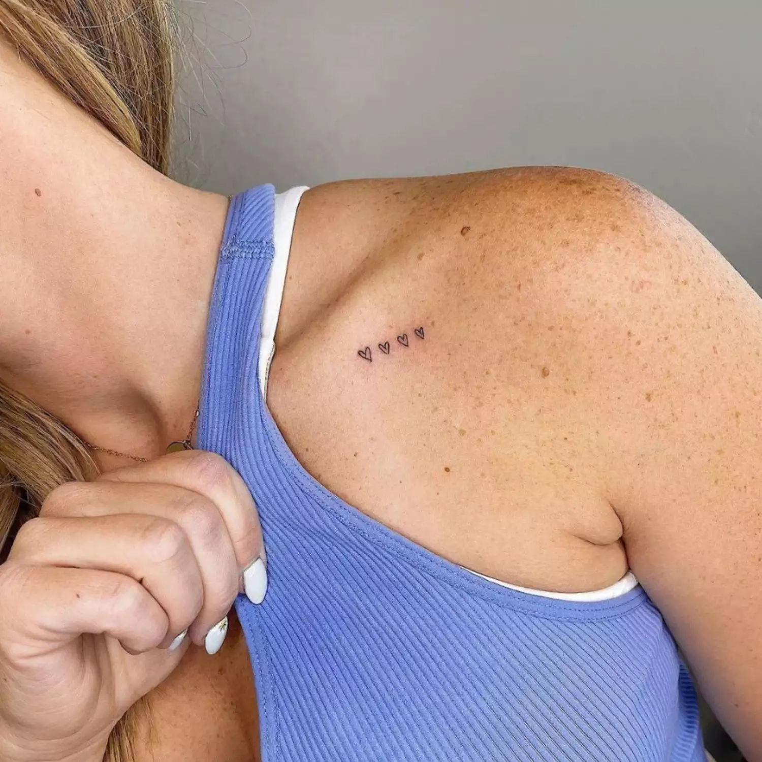 zoomed-in image of model with four small open heart tattoos on collarbone