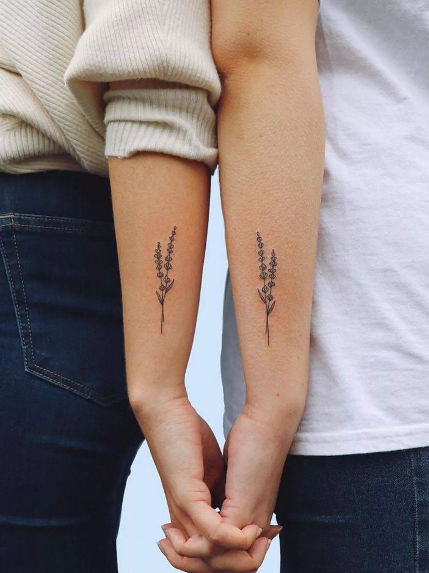 Friends with matching lavender sprig tattoos on forearms