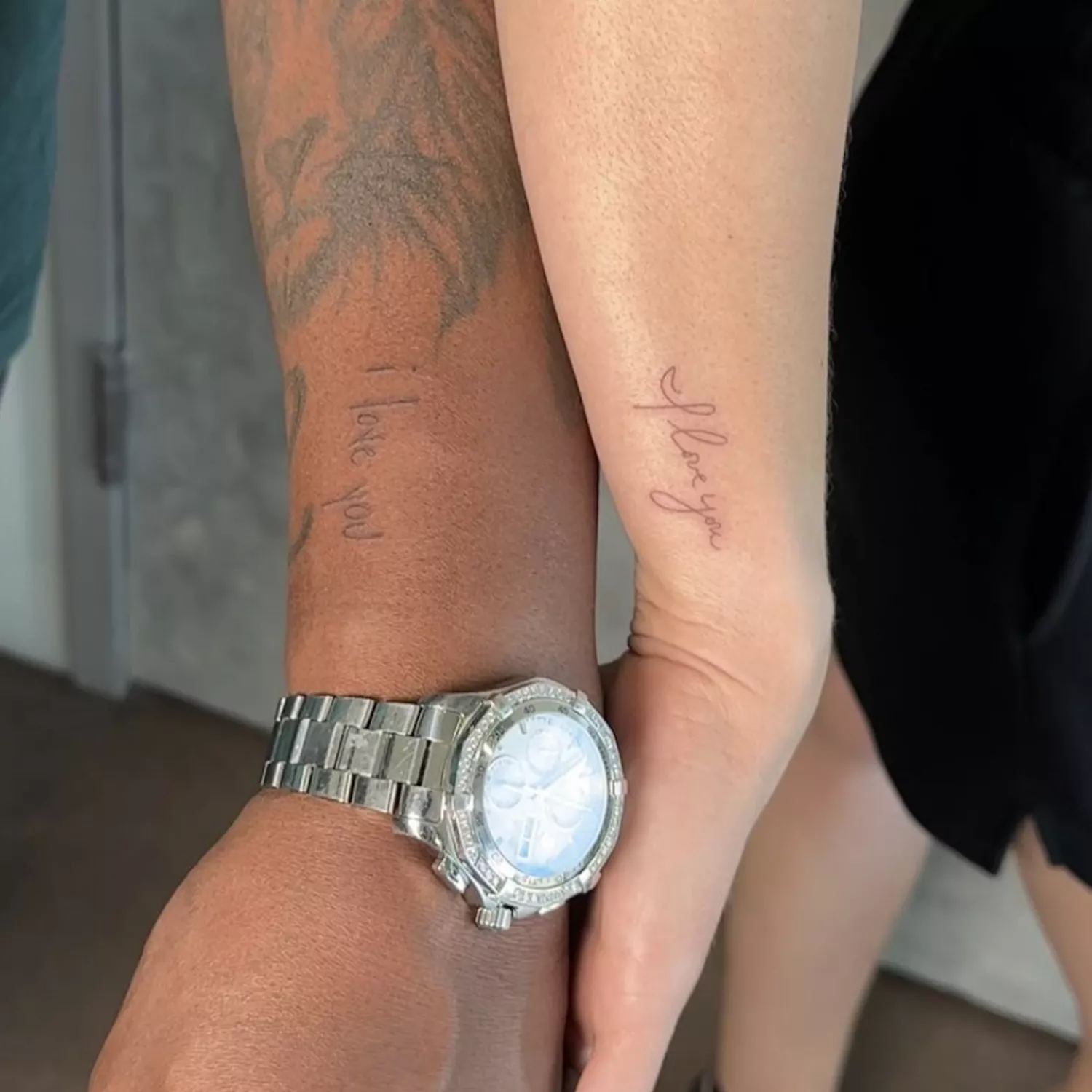 Couple with matching arm tattoos that say "I love you" in handwritten scripts