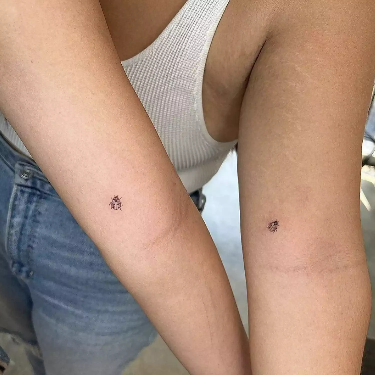 Friends with matching ladybug tattoos on arms