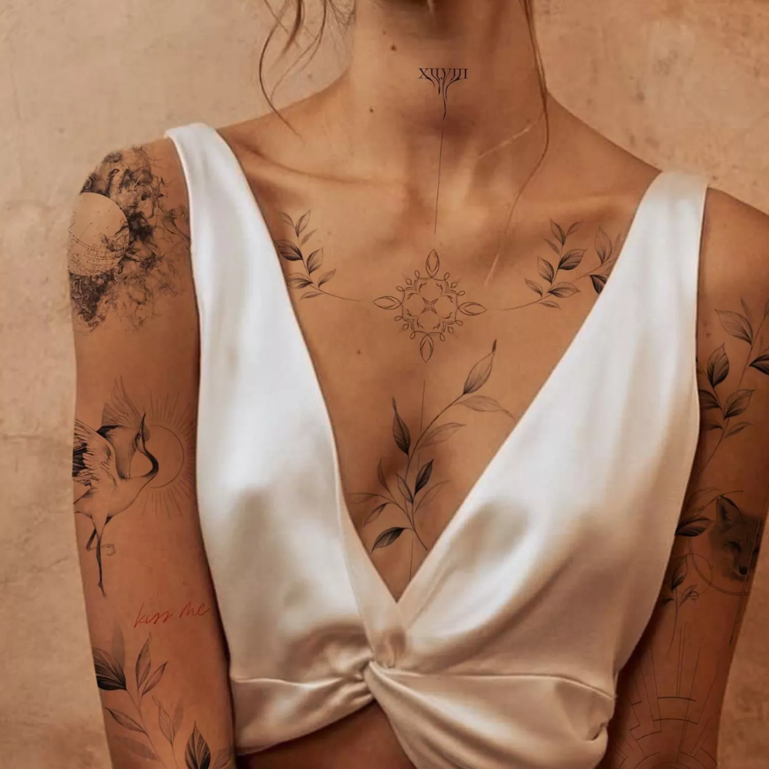 zoomed in image of model with fine line tattoos on chest, neck, and collarbone - thin line work, dainty flowers and shapes